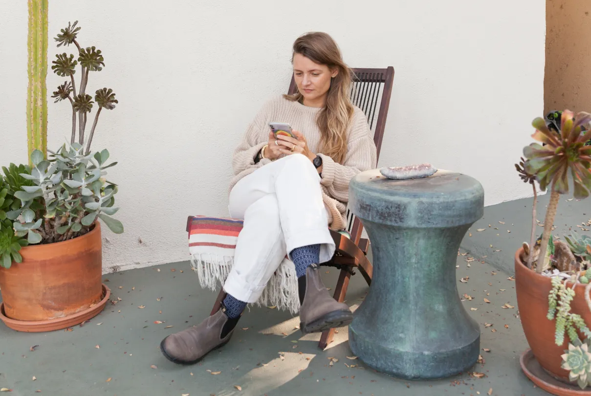 Someone looking at their phone on a foldable chair.